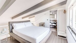 Ein Schlafzimmer mit Bett, Stuhl, kleinem Tisch, Kleiderschrank und Fenster.