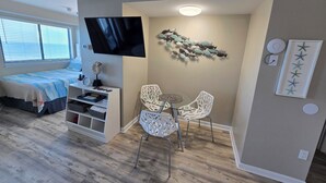 A compact living space with a bed, TV, dining area, and decorative wall art. - Beachy 7th floor studio @ Myrtle Beach Resort (Myrtle Beach)