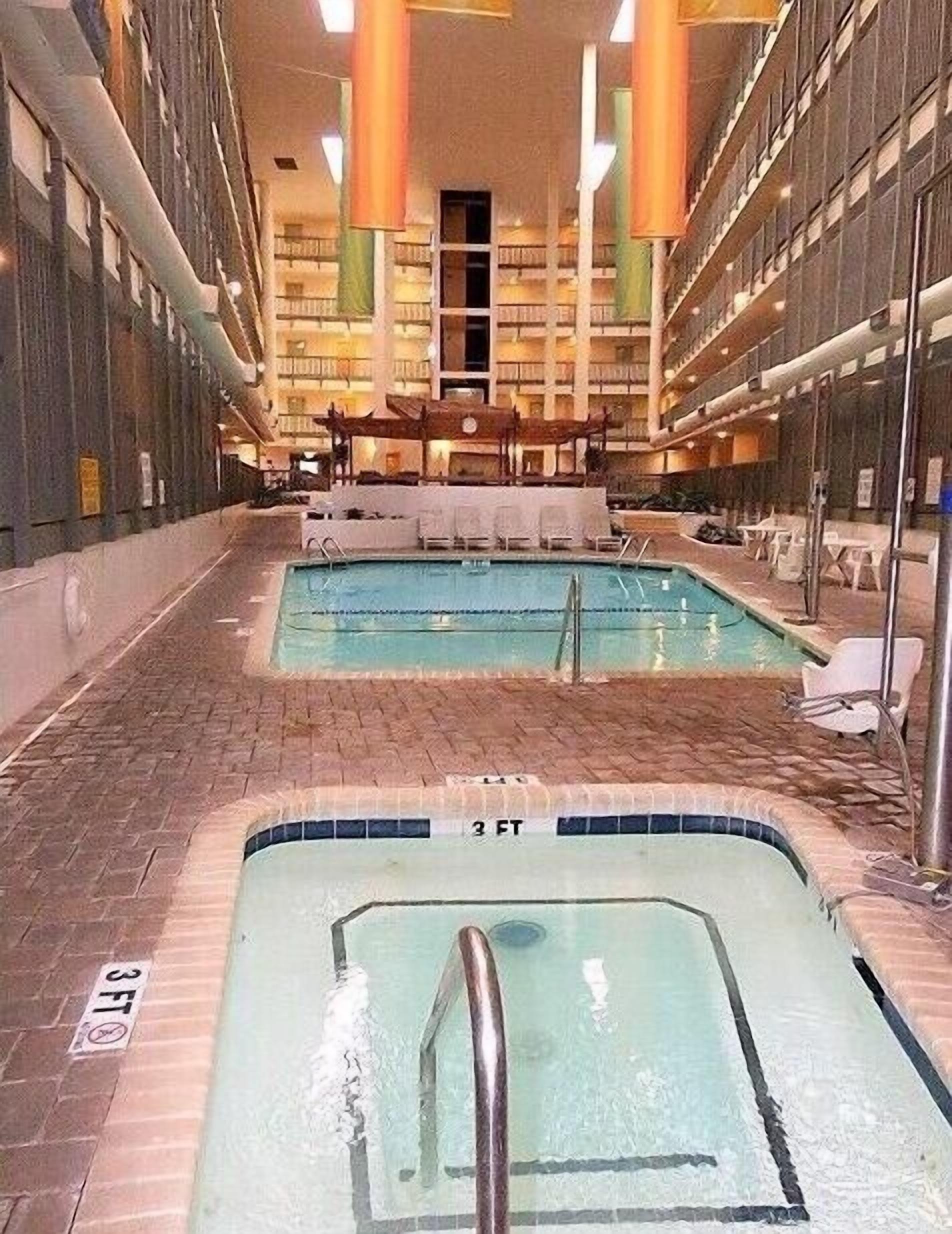 Ein Innenbereich mit Schwimmbecken, Liegestühlen und einem Fliesenboden.