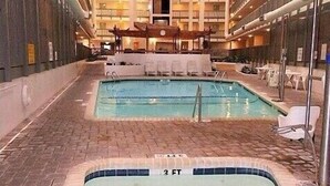 An indoor swimming pool area with two pools, lounge chairs, and a brick floor. - Beachy 7th floor studio @ Myrtle Beach Resort (Myrtle Beach)