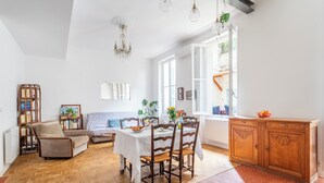 Un amplio salón con comedor, muebles de madera y un ventanal grande que proporciona luz natural.
