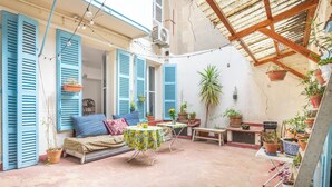 Un patio exterior con un sofá, una mesa y plantas en macetas.