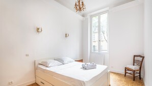 Un dormitorio con cama, una silla y una ventana.