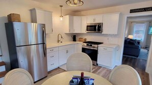 Una cucina moderna con mobili bianchi, elettrodomestici in acciaio inossidabile e zona pranzo con un tavolo rotondo e sedie.