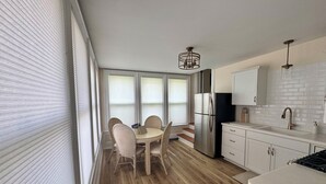 Una cucina moderna con frigorifero in acciaio inox, mobili bianchi e pavimento in legno.