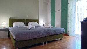 A neatly made bed with pillows and a blanket, a bedside table with a lamp, and a wardrobe with a green panel.