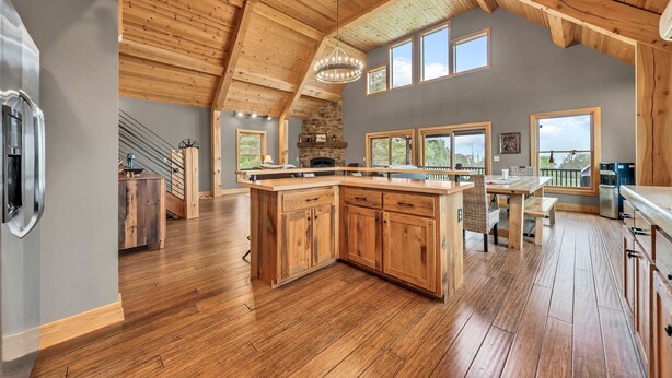 A spacious kitchen with wooden cabinets, a large island, and a stone fireplace. - Spacious Ellicottville 5-bedroom 4-bath chalet with WiFi, AC (East Otto)