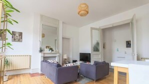 A modern living room with a sofa set, a dining table, and a TV. - Arras • 2 ch • Balcon • Parking gratuit • Standing (Arras)