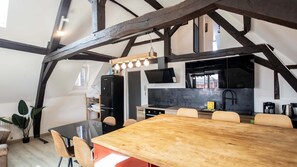 A modern kitchen with a black refrigerator, a microwave, and a wooden dining table with chairs. - Loft à Arras • 3 ch • 7 personnes • hypercentre (Arras)