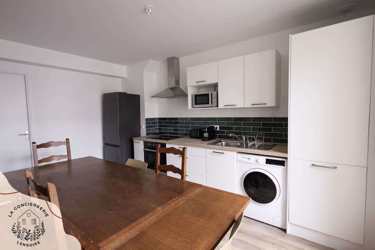 Una cocina compacta con armarios blancos, un microondas, una estufa y una lavadora.