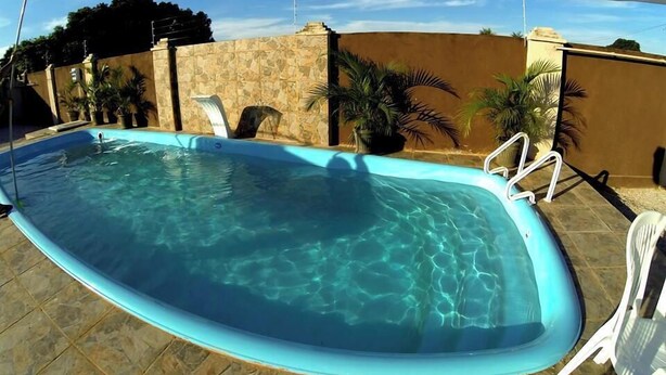 Una piscina con agua cristalina, rodeada por un muro de piedra y plantas en macetas.