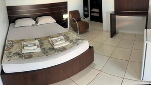 Una habitación de hotel con una cama curvada, una silla, un escritorio y una televisión.