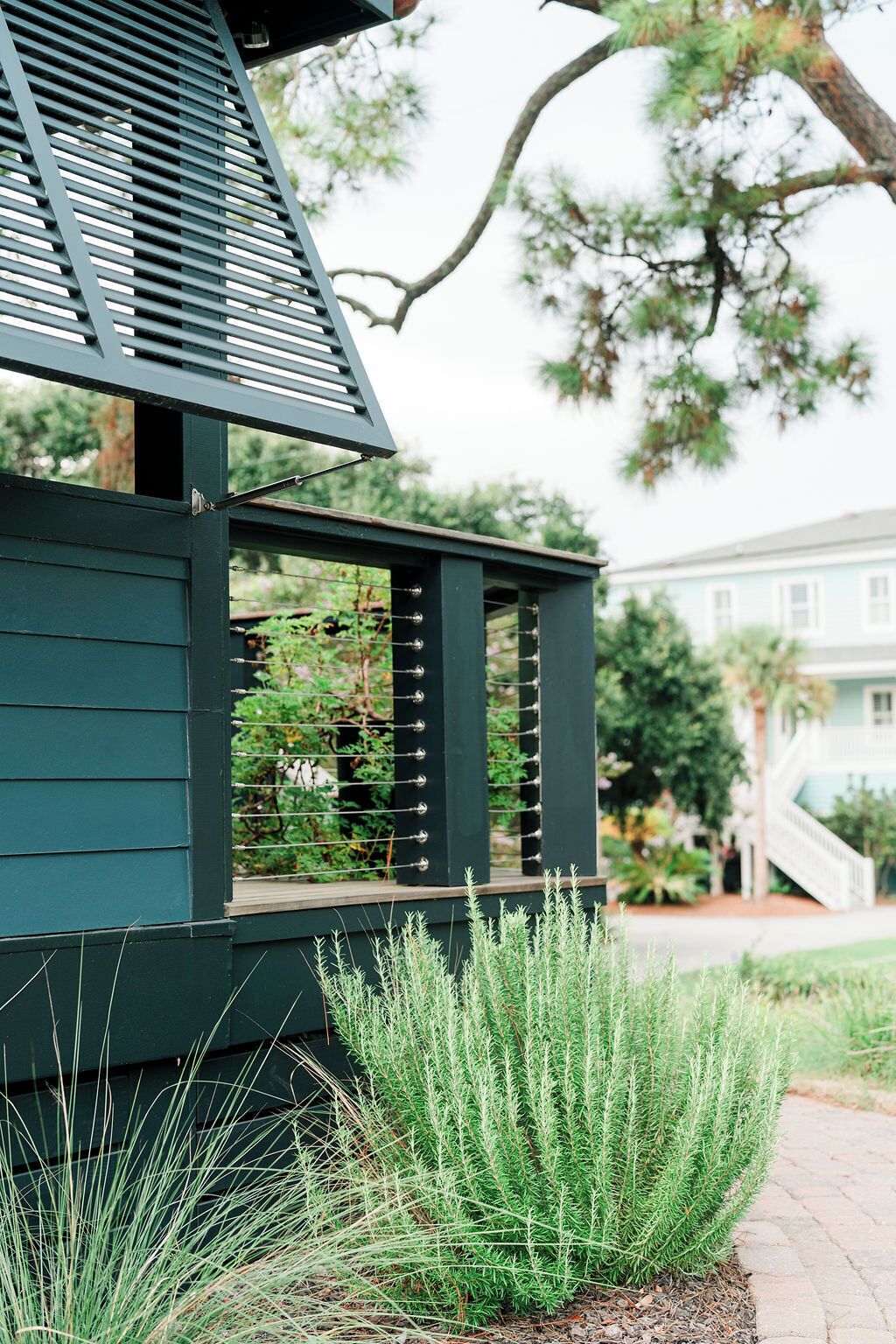 Un bâtiment vert avec une fenêtre et une porte, entouré d’herbe et d’un arbre.
