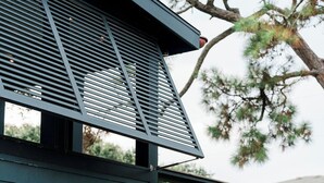 Un edificio moderno con fachada oscura, techo inclinado y una ventana visible.