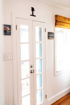 A white door with a keyhole and a small black object above it. - 2BR Folly Cottage 1-block from the beach! (Folly Beach)