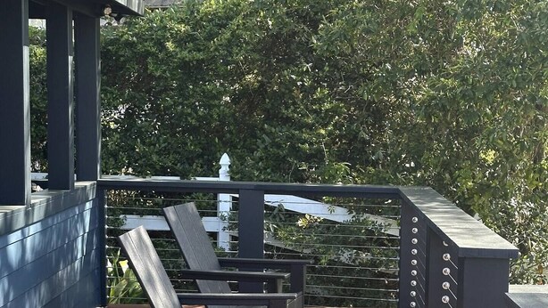 Una terraza de madera con dos sillones de descanso y una planta en maceta.