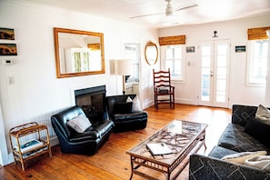 A living room with a fireplace, leather sofas, a coffee table, and a ceiling fan.