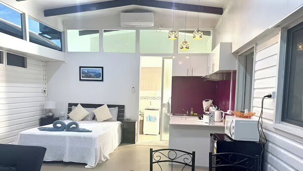 Een kleine hotelkamer met een bed, een tafeltje en een kitchenette.