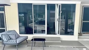 Een moderne woonkamer met een grijze bank, een kleine zwarte tafel en een schuifdeur naar een patio.