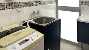 Een moderne badkamer met een ingebouwde wasmachine, een wastafel en een raam.