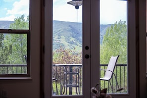 A room with a sliding glass door leading to a balcony with a chair and a table.