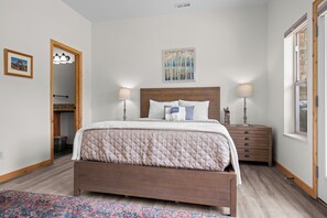 A bedroom with a wooden bed, two bedside lamps, a nightstand, a framed picture, and a painting on the wall. - Mountain View Retreat MH1007| Pool |Hot Tub |Sauna (Eden)