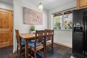 Une cuisine équipée d’une table à manger, de chaises, d’un réfrigérateur, d’une fenêtre avec vue et d’un tableau accroché au mur.