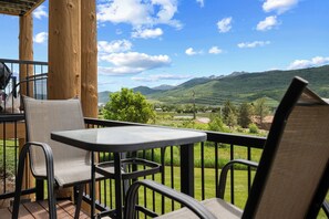 Un balcon avec une table et des chaises, donnant sur un paysage montagneux.