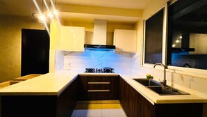 Cocina pequeña con estufa a gas, un lavamanos y armarios de madera.