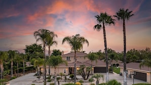 A residential property with a two-story house, a driveway, and a well-maintained garden with palm trees. - Villa Verdot | 6BR Estate w/ Pool, Tennis, Basketball (Temecula)