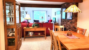 A dining area with a wooden table, chairs, and a hanging light fixture.