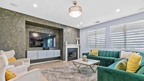 Una sala de estar moderna con chimenea, sofás verde y blanco, y un televisor de pantalla plana montado en una pared con textura.