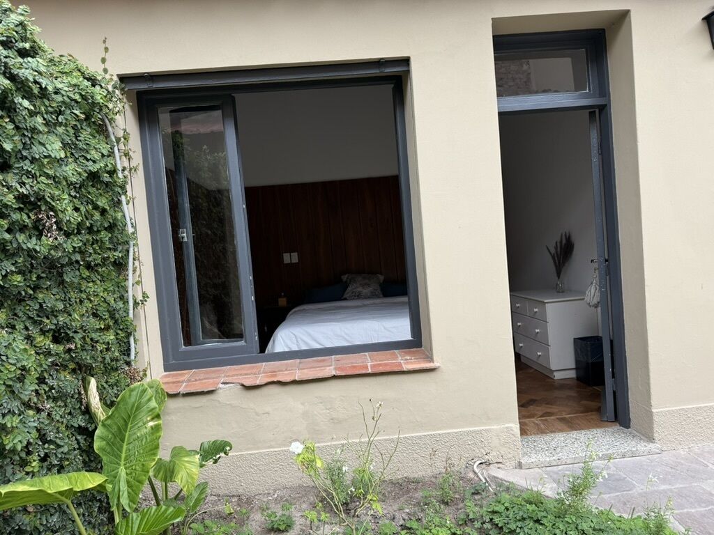 Un dormitorio con un ventanal grande, una cama y un pequeño escritorio.