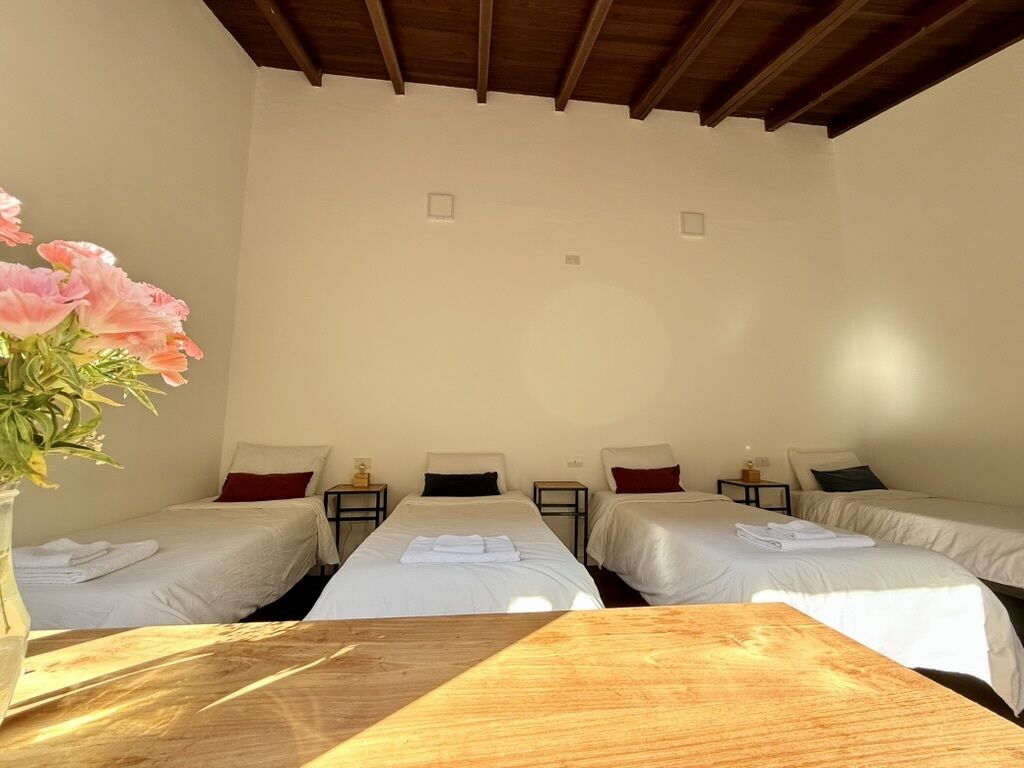 A hotel room with two single beds, a wooden table, and a vase with flowers.