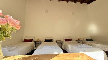 A hotel room with two single beds, a wooden table, and a vase with flowers.