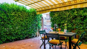 Eine Terrassengruppe mit Esstisch, umgeben von üppigem Grün und einem gefliesten Boden.