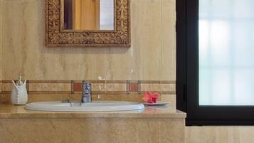 Un baño con lavamanos de mármol, un espejo decorativo y una ventana con vidrio esmerilado.