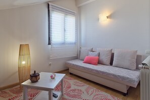 Uma sala de estar com sofá, mesa, luminária e janela com persianas.