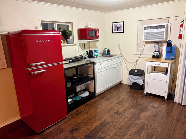 A compact kitchen with a red refrigerator, a microwave, a sink, and a coffee maker. - Cozy Waterfront Cabin Minutes from the Beach (Palacios)