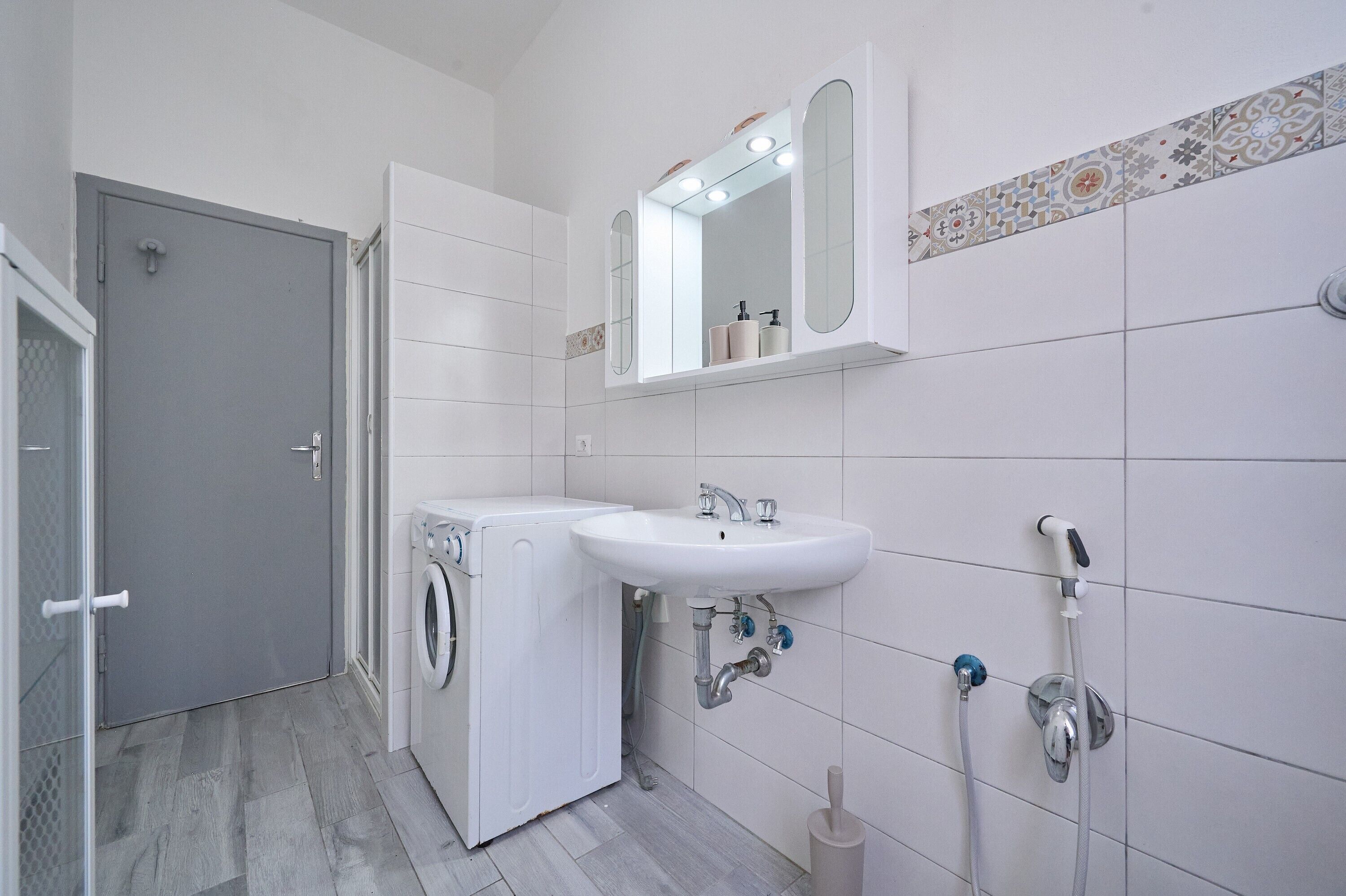 Une salle de bain équipée d’un lave-linge, d’un évier et d’une douche.