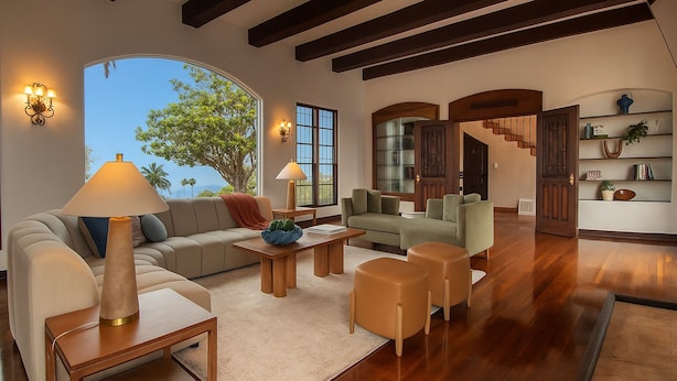 A spacious living room with a large window, a sofa, a coffee table, and a bookshelf. - Epic Resort Villa: Pool, Spa, Firepit, Ocean View, Games (San Diego)