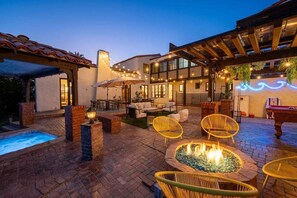 Un patio con piscina, mobiliario exterior y una chimenea.