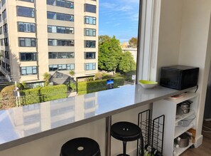 A modern kitchen with a large window, a microwave, and a view of a cityscape.