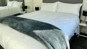 A hotel room with a large bed, two bedside tables, and a nightstand.