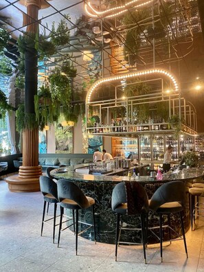 Een bar met een gebogen toonbank, barstoelen en een barman.