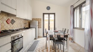 A modern kitchen with a dining area, featuring a stove, oven, refrigerator, and a dining table with chairs. - Holiday Home 'Casa Spaziosa' with Air Conditioning (Bari Sardo)