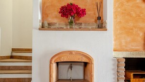 A fireplace with a brick arch, a shelf with flowers, and a wooden bench. - Holiday Home 'Casa Spaziosa' with Air Conditioning (Bari Sardo)
