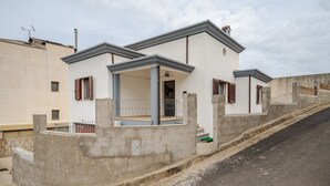 A modern two-story building with a covered patio, concrete walls, and a sloped roof. - Holiday Home 'Casa Spaziosa' with Air Conditioning (Bari Sardo)