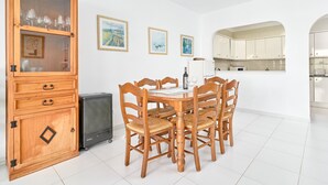 A dining area with a wooden table and chairs, a cabinet with glass doors, and a kitchen in the background. - Holiday Home 'Casa Del Sol' with Sea Views, Wi-Fi and Air Conditioning (Nerja)
