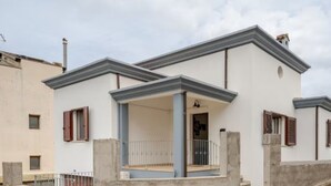 Un bâtiment à deux étages doté d’un balcon, d’une porte et d’une fenêtre avec des volets.